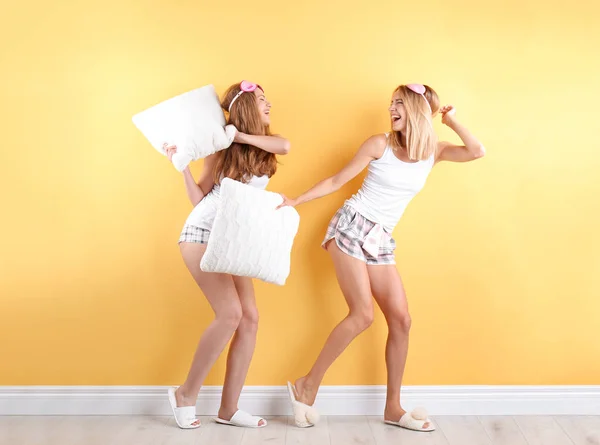 Dos Mujeres Jóvenes Teniendo Pelea Almohadas Cerca Pared Color —  Fotos de Stock