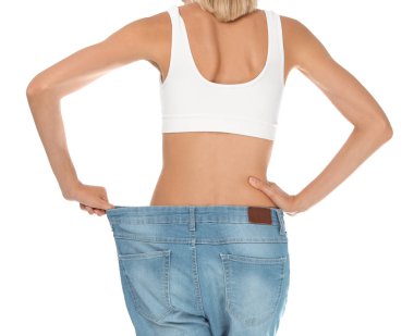 Eski büyük kot pantolon onun diyet sonuçları beyaz arka plan üzerinde gösterilen genç ince kadın