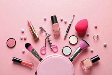 Pastel pembe arka planda dekoratif makyaj ürünleri ile düz konum