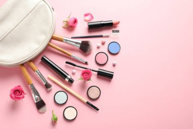 Pastel pembe arka planda dekoratif makyaj ürünleri ile düz konum