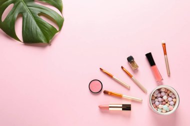 Pastel pembe arka planda dekoratif makyaj ürünleri ile düz konum