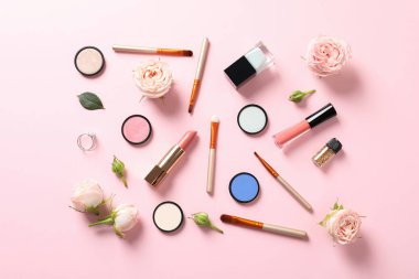 Pastel pembe arka planda dekoratif makyaj ürünleri ile düz konum