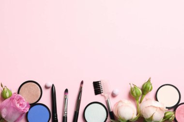 Pastel pembe arka planda dekoratif makyaj ürünleri ile düz konum