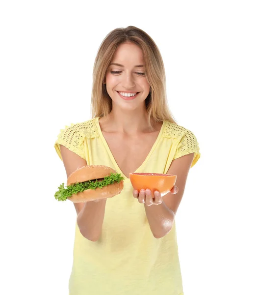 白い背景の上のハンバーガーとグレープ フルーツを保持している若い女性 食事と不健康な食品の選択 — ストック写真