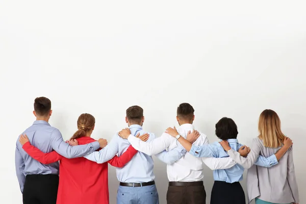 Group of young people hugging each other on light background. Teamwork concept