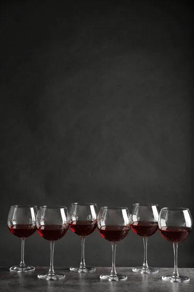 Glasses with red wine on table against dark background