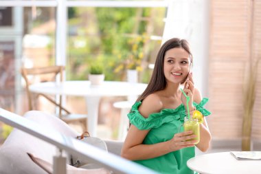 Genç kadın cep telefonuyla içme lezzetli sağlıklı güler yüzlü süre masada kapalı