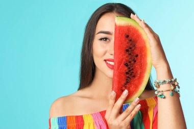 Renkli arka planda karpuzla poz veren güzel genç bir kadın.