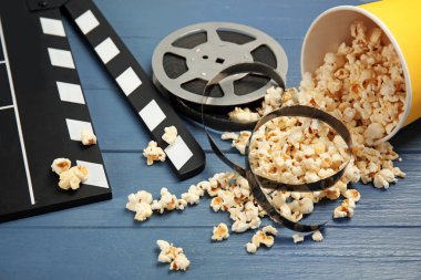 Patlamış mısır, film makaraları ve ahşap arka plan üzerinde Klaket ile kompozisyon