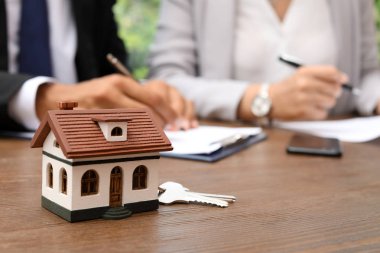 Emlakçı ofiste tabloda anahtarları ve ev modeli
