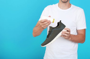 Toz temizleyici renk arka plan üzerinde ayakkabı koyarak adam