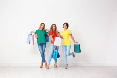 Grup alışveriş torbaları ışık duvarının yakınında olan genç kadın