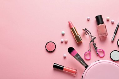 Pastel pembe arka planda dekoratif makyaj ürünleri ile düz konum