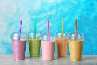 Renk arka plan karşı masada smoothies ile plastik bardak