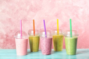 Renk arka plan karşı masada smoothies ile plastik bardak