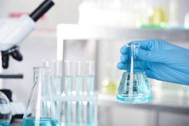 Şişe sıvı olan laboratuvar, closeup tutan analisti. Kimyasal analiz