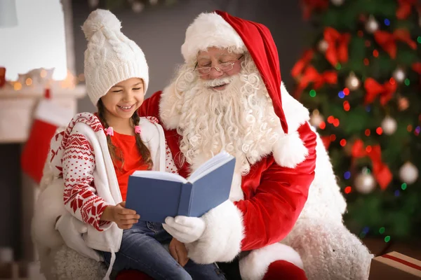 Маленькая Девочка Читает Книгу Сидя Коленях Настоящего Санта Клауса Помещении — стоковое фото