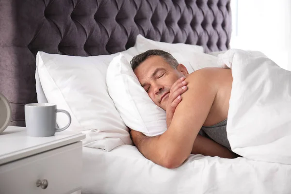 Man sleeping on comfortable pillow in bed at home