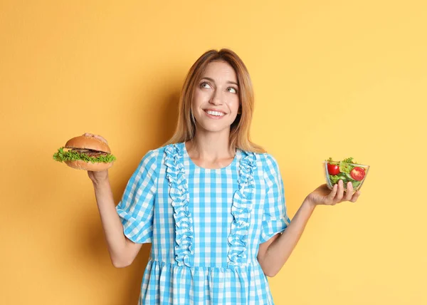 Młoda Kobieta Gospodarstwa Burger Sałatka Kolor Tła Wybór Pomiędzy Dietą — Zdjęcie stockowe