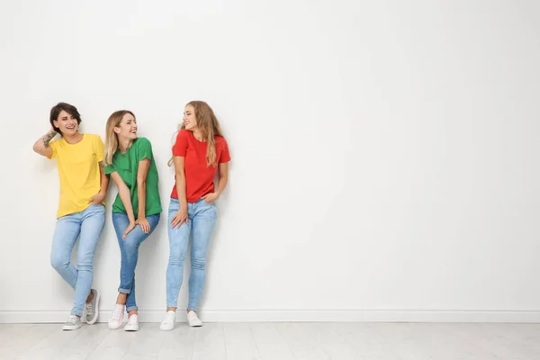 ジーンズと光壁の近くのカラフルな シャツの若い女性のグループ — ストック写真