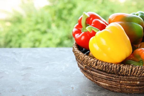 Bowl with ripe paprika peppers on table against blurred background