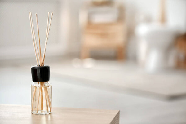 Aromatic reed air freshener on table against blurred background
