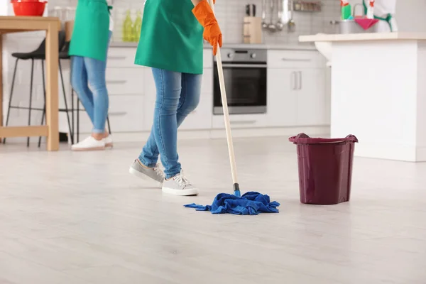 Woman cleaning floor with mop in kitchen, closeup