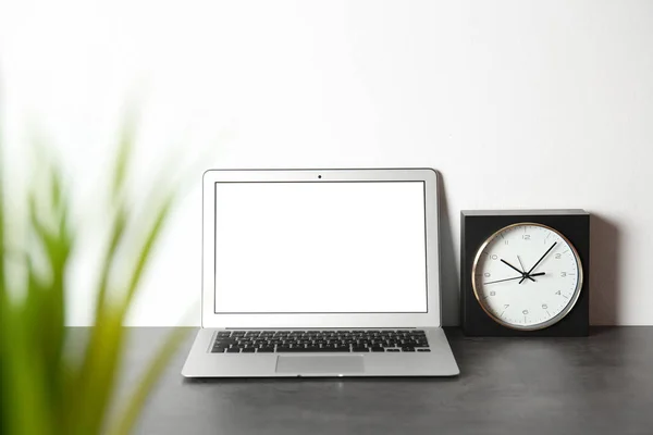 Modern laptop monitor on table against white wall. Mock up with space for text