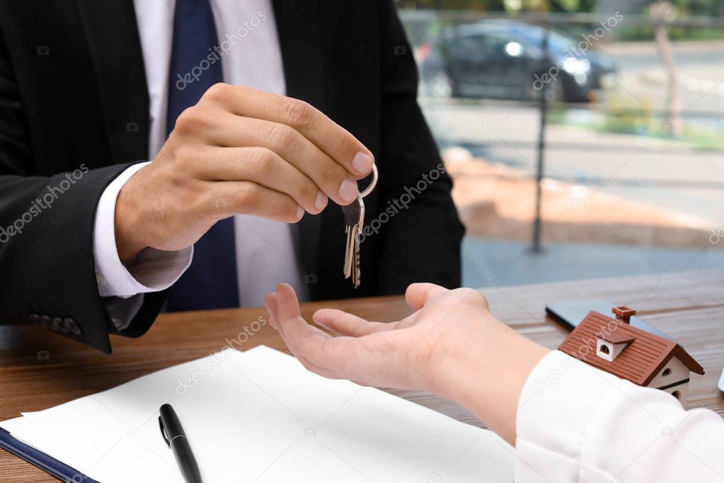Real estate agent giving keys to woman at table