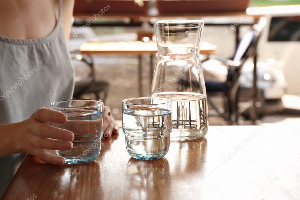 Woman with glass of water at table indoors