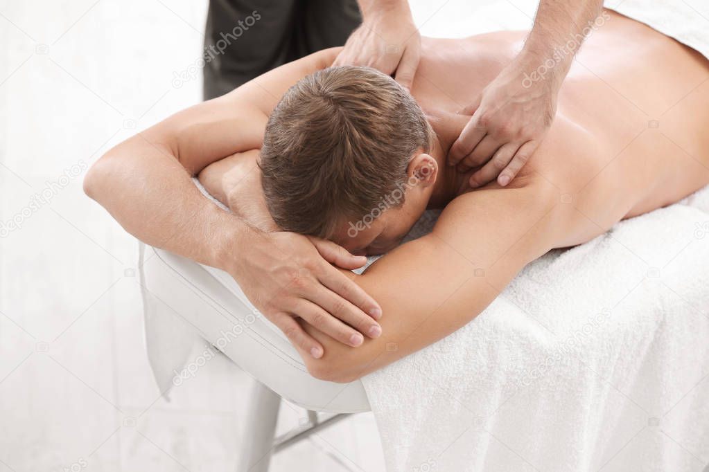 Relaxed man receiving back massage in wellness center