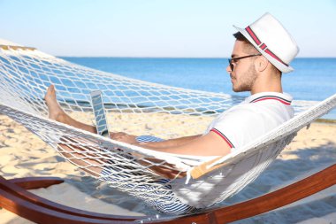 Sahil, hamakta dinlenme dizüstü bilgisayar ile genç adam