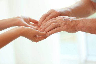 Bulanık arka planda, closeup eller genç kadın yaşlı adam tutarak. Yardım hizmeti