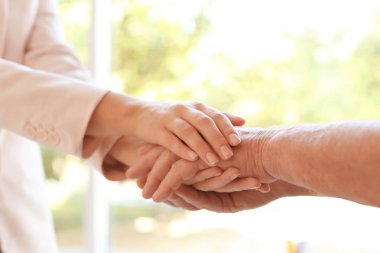 Bulanık arka planda ellere yardım etmek, yakın çekim. Yaşlılara bakım kavramı