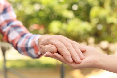 Bulanık arka planda ellere yardım etmek, yakın çekim. Yaşlılara bakım kavramı