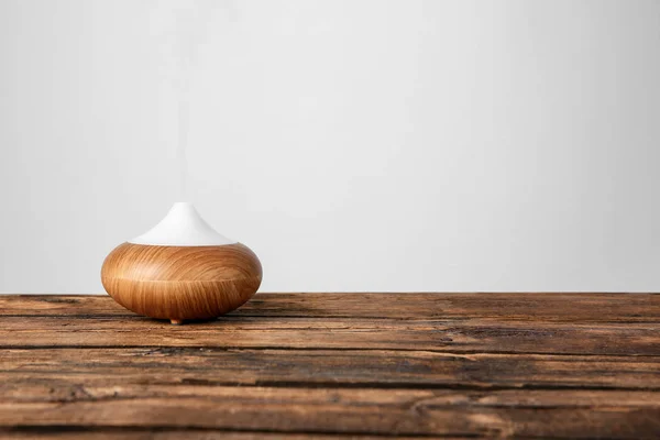 Aroma oil diffuser lamp on table against light background