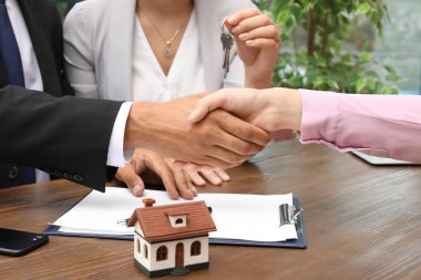 Man shaking hands with real estate agent on meeting over table clipart