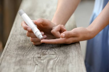 Açık havada ahşap yüzeye yakın mazgal kalem kullanan kadın. Diyabet kontrolü
