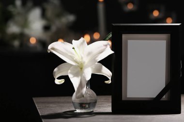 Cenaze fotoğraf çerçevesi siyah şerit ve karanlık odada masada lily ile