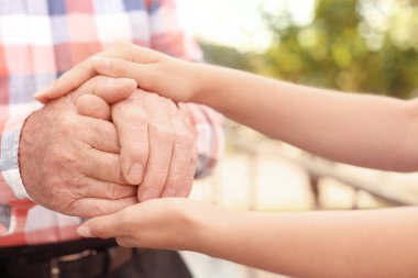 Bulanık arka planda ellere yardım etmek, yakın çekim. Yaşlılara bakım kavramı