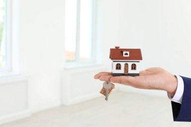 Emlakçı ev modeli ve anahtar arka plan bulanık üzerinde closeup holding