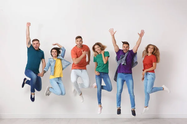 Группа Молодых Людей Джинсах Разноцветных Футболках Прыгающих Возле Светлой Стены — стоковое фото