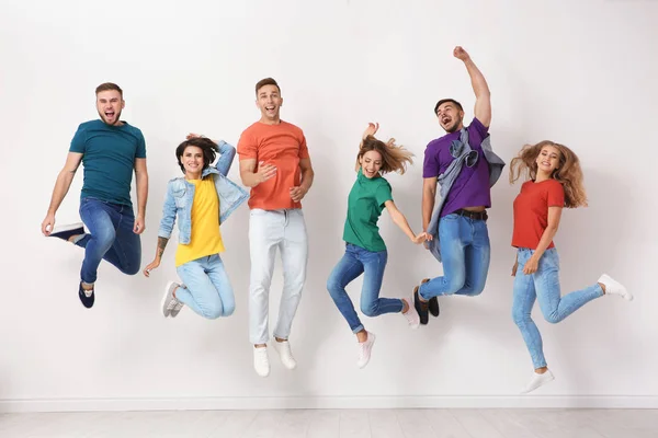 Grupo Jóvenes Jeans Camisetas Colores Saltando Cerca Pared Luz — Foto de Stock