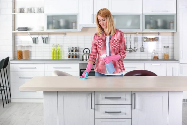 Woman cleaning table with rag in kitchen