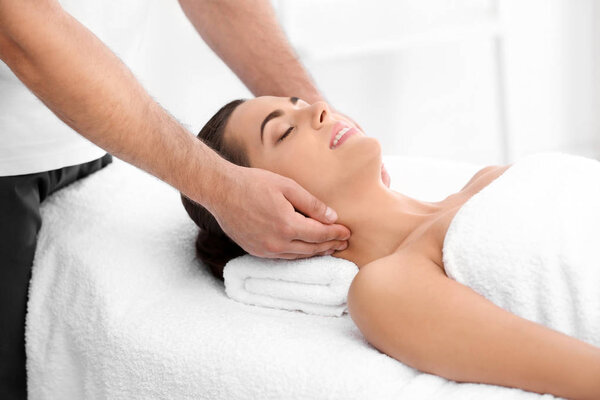 Relaxed woman receiving neck massage in wellness center