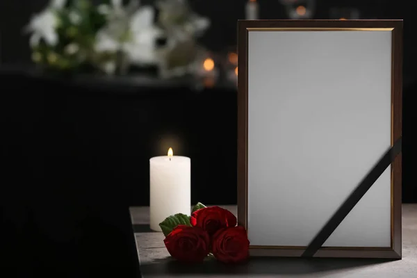 黑丝带 玫瑰和燃烧蜡烛在黑暗的房间桌子上的葬礼相框 — 图库照片