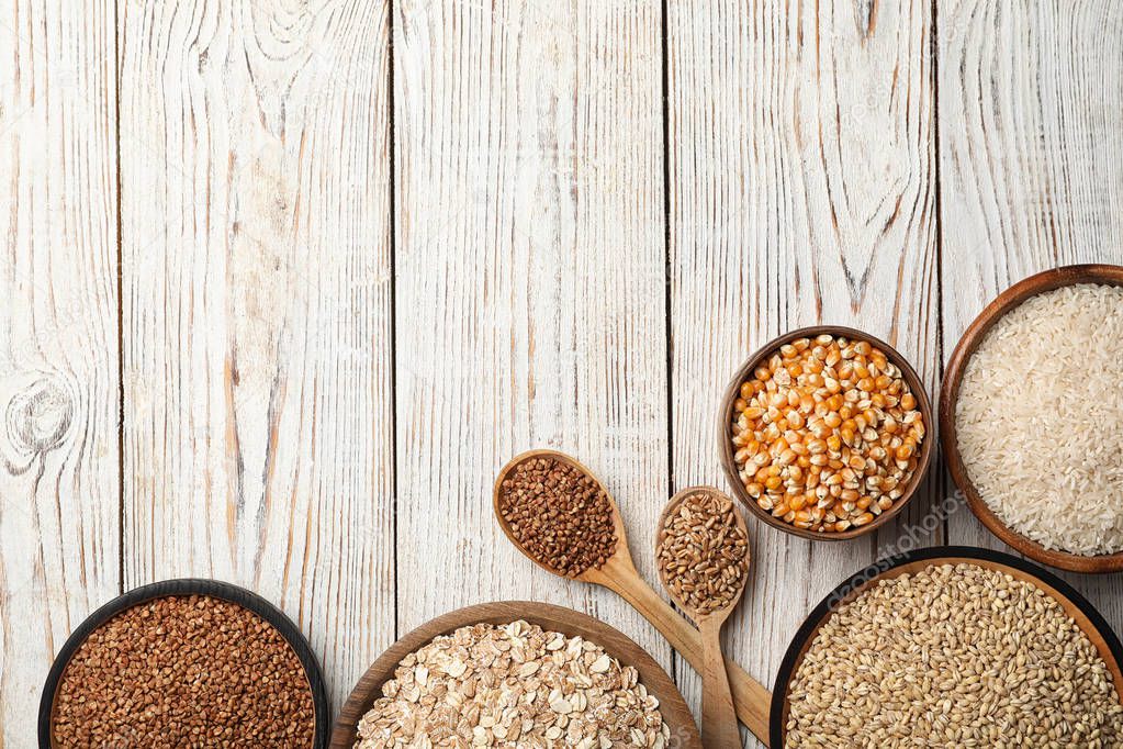 Flat lay composition with different types of grains and cereals on wooden background
