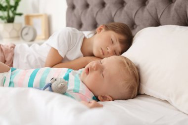 Küçük çocuklar evde yatakta uyuyor