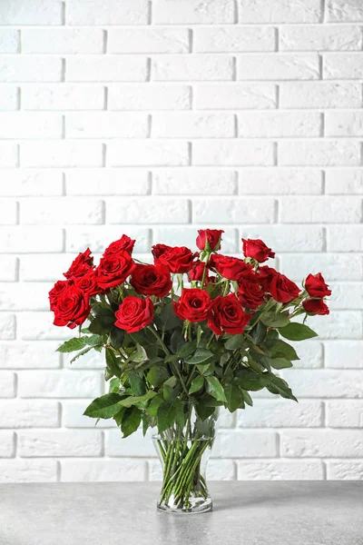 Vaso Com Belas Rosas Vermelhas Mesa Contra Fundo Parede Tijolo — Fotografia de Stock