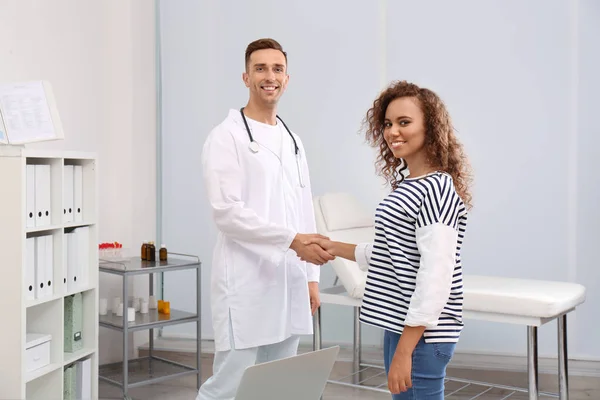 Doctor and African American patient shaking hands in hospital